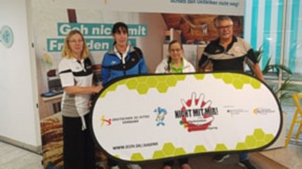 Die Bürgermeisterin von Walsrode und Mitarbeiterinnen und Mitarbeiter unterschiedlicher Einrichtungen vor einer Holztreppe.